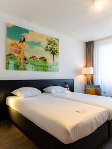 阿尔克马尔Hotel Alkmaar的卧室配有一张大床,墙上挂有绘画作品