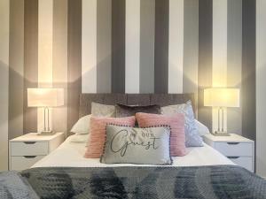 科尔切斯特Luxury Suite in Colchester Town Centre By Station的一间卧室配有一张带枕头的床和两盏灯。