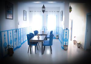 舍夫沙万CASA BLUE PEARL的一间带桌子和蓝色椅子的用餐室