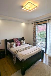 内罗毕Urban Haven 3BR Apartment的卧室配有带枕头的床铺和窗户。