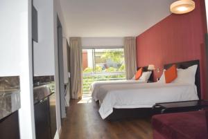 布宜诺斯艾利斯Hotel BA Abasto的酒店客房设有两张床和红色的墙壁。