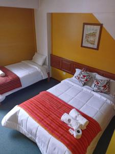 瓦拉斯Huaraz Center Hostal的酒店客房,配有两张带毛巾的床