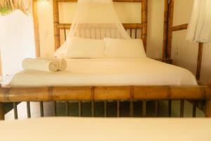 伯里塔卡Playa Bonita Hotel EcoCabañas Tayrona的一张带白色床单和毛巾的床