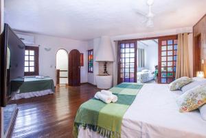 伊利亚贝拉Pousada Recanto da Villa的一间卧室配有一张大床和电视