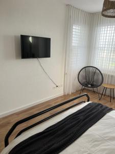 UzwilBlack&White Apartment的卧室配有一张床和壁挂式平面电视。