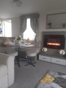 韦茅斯Littlesea Haven Weymouth的客厅配有桌子和壁炉