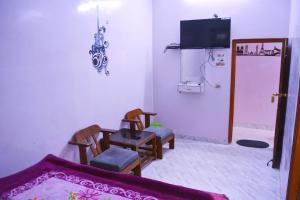 克久拉霍Hostel shivshakti khajuraho的客厅配有两把椅子、一张桌子和一台电视