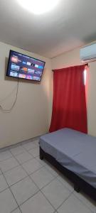 Colonia AlamitosConfortable habitación的一间卧室配有一张带红色窗帘的床和一台电视。