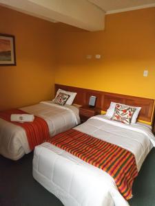 瓦拉斯Huaraz Center Hostal的黄色墙壁客房的两张床