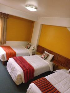 瓦拉斯Huaraz Center Hostal的一间酒店客房内设有三张床的房间