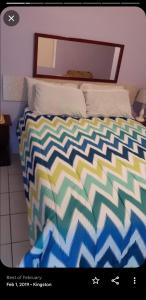 金斯敦Cliff Apartment的卧室内一张带五颜六色棉被的床