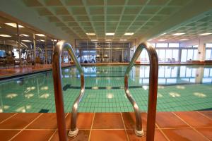 贝特斯托尔贝特斯托尔丽笙度假酒店的前面有一个带金属栏杆的游泳池