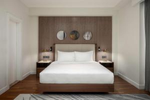 埃尔比勒Radisson Hotel & Residences Erbil的卧室配有一张白色的大床和两张桌子