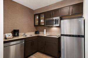 兀兰休斯敦伍德兰兹/市集大街原住客栈的厨房配有棕色橱柜和不锈钢冰箱