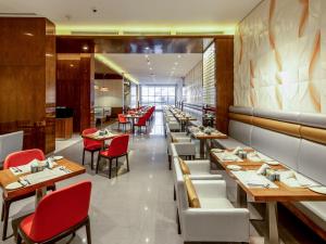 迪拜Flora Al Barsha Hotel At The Mall的用餐室配有桌子和红色椅子