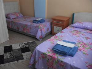 恰纳卡莱厄尔努尔旅馆的一间卧室配有两张带紫色床单和一张桌子的床。