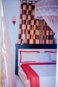 基加利SILVER HOTEL APARTMENT Near Kigali Convention Center 10 minutes的一间卧室配有一张带红色和深色窗帘的床