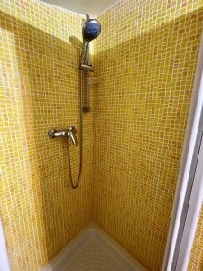 墨西拿Sicilia Bedda Apartment的带淋浴头的黄色瓷砖浴室
