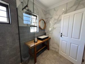 东伦敦Coral Tree Boutique Guesthouse的一间带镜子和木桌的浴室