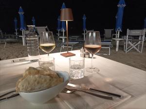 皮昂比诺Seashell Piombino的一张桌子,上面放着两杯葡萄酒和一碗面包