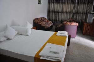 亭可马里Trinco Rest House的一间卧室配有一张大床、两张椅子和毛巾