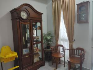 峇冬加里As Salam Musliim Homestay的一间房间里有一个祖父钟和两把椅子