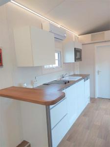 武斯特马克Tiny House Paradies的厨房配有白色橱柜和木制台面