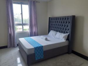 蒙巴萨TWO BEDROOM APARTMENT BAMBURI Mombasa的卧室内的一张床铺,设有大窗户