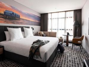 珀斯Novotel Perth Murray Street的酒店客房设有一张大床和一张书桌。
