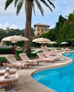 圣玛格丽塔-利古雷米拉梅尔大酒店的游泳池旁的一排躺椅和遮阳伞