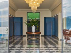 圣玛格丽塔-利古雷米拉梅尔大酒店的走廊上带有蓝色门的桌子上的花瓶