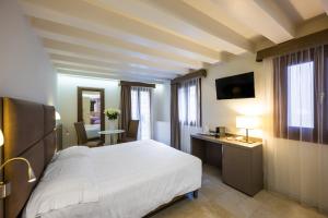 威尼斯Leone Hotel的一间卧室配有一张床、一张书桌和一台电视