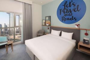 迪拜Rove City Walk的一间卧室,配有一张床和一个标志,上面写着旅行新路