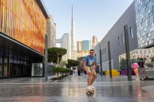 迪拜Rove City Walk的沿着城市街道骑滑板的人