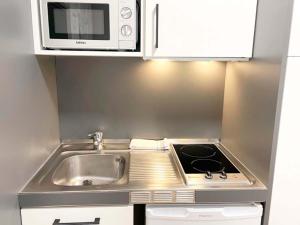 福米加尔Apartamentos Midi 3000的一间带水槽和微波炉的小厨房