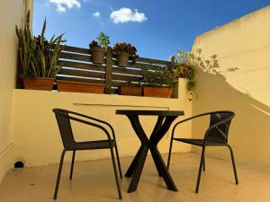 卢加Private One Bedroom Apartment close to Airport in Luqa的植物阳台的两把椅子和一张桌子