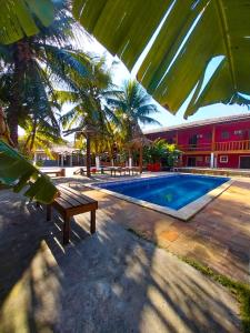 布希奥斯Super Flats Geribá的一个带长凳和棕榈树的游泳池以及一座建筑