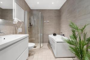 特罗姆瑟Enter City Apartment Hotel的浴室配有白色浴缸、卫生间和水槽。