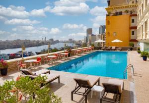 迪拜卡尔顿塔酒店的一座带桌椅的建筑屋顶上的游泳池