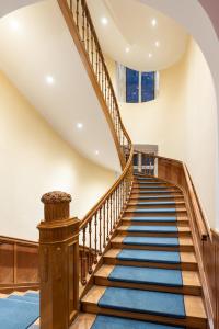 巴特基辛根Villa Thea Hotel am Rosengarten的 ⁇ 的楼梯,有木栏杆和蓝色地毯
