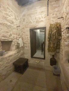 塞拉莱نزل كوفان التراثي Koofan Heritage Lodge的石质浴室设有镜子和凳子
