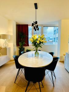 布鲁塞尔Urbanstay Suites Grand Place Luxury Apartment的用餐室配有桌椅,并摆放着黄色的鲜花