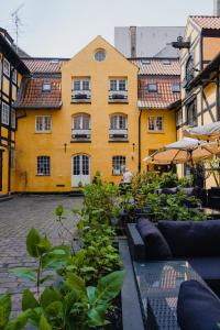 哥本哈根Capsule Hotel Nyhavn63的一座黄色的建筑,前面有大量的植物