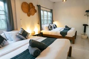 清迈Baan Ragang : Cozy Entire House in Old Chiang Mai的一间卧室设有两张床和两个窗户。