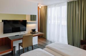 施韦夏特HEINhotel vienna airport的酒店客房配有一张床和一张书桌及一台电视