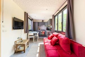 BandeTinyhouses - Domain "La vallée des Prés"的一间带红色沙发的客厅和一间厨房