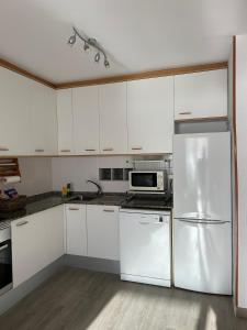 克尤伯厄拉斯Apartment Foix的厨房配有白色橱柜和不锈钢冰箱