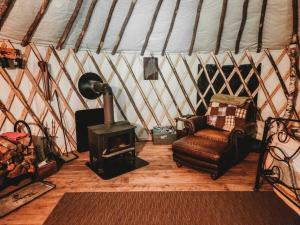BrownfieldRufus III Yurt on the river的蒙古包内带炉灶和椅子的客房