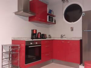 勒罗贝尔A L'Arche Bleue的厨房配有红色橱柜和黑色烤箱