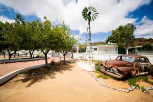 斯普林博克Kleinplasie Guesthouse的一辆停在风车旁边的旧车